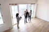 a couple and their baby look at a place with a business woman in front of open patio doors